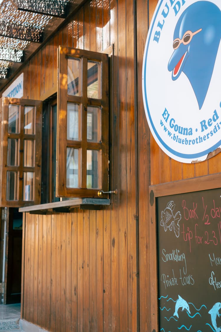 Wooden building with open windows and a blue dolphin logo sign on the side.