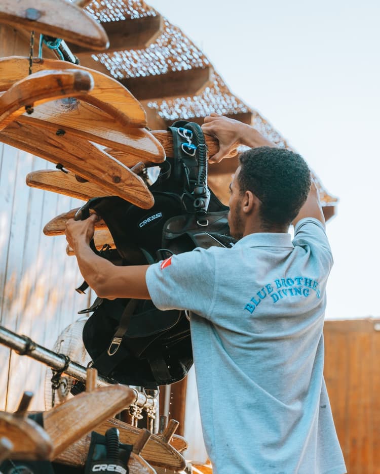Man organizing wooden hangers outdoors, with a bag hanging among them.