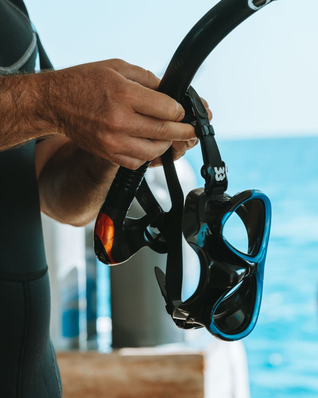 Hands hold a black snorkel mask and breathing tube.