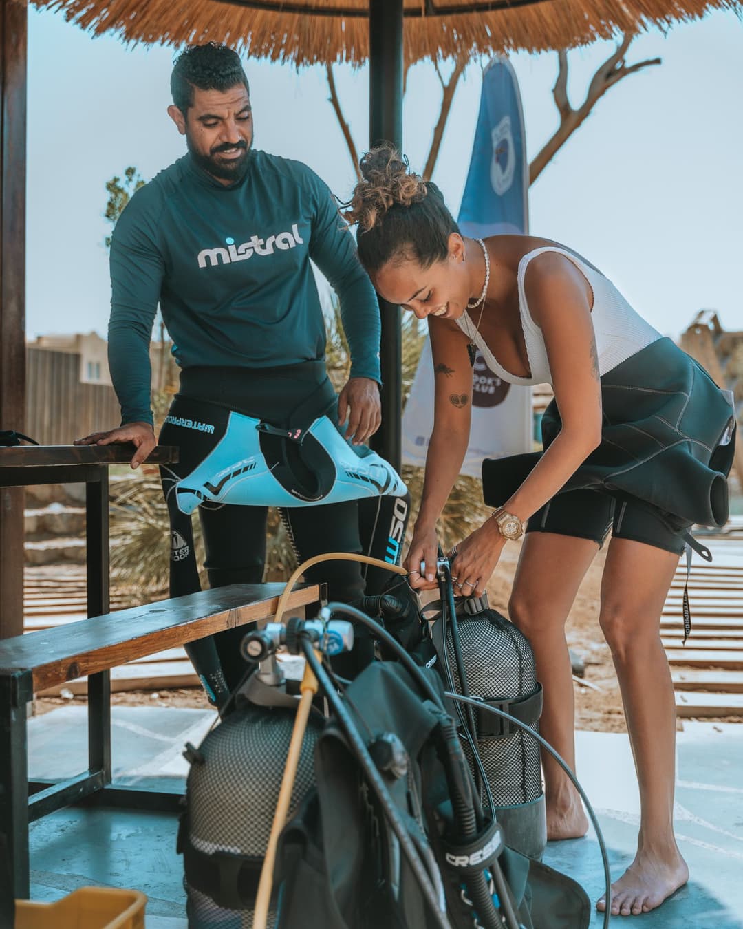 A man and woman assembling their scuba diving equipment on an outdoor bench.