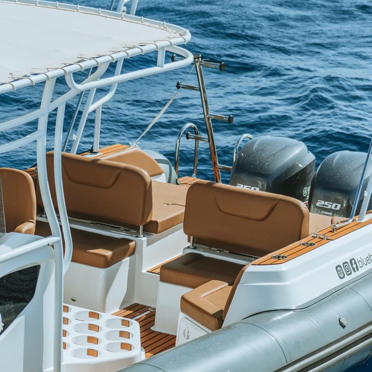 Rear view of a boat with comfortable brown seating and twin outboard engines.
