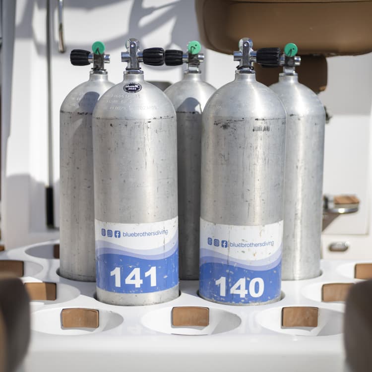 Several scuba tanks with labels "141" and "140" arranged on a boat deck.